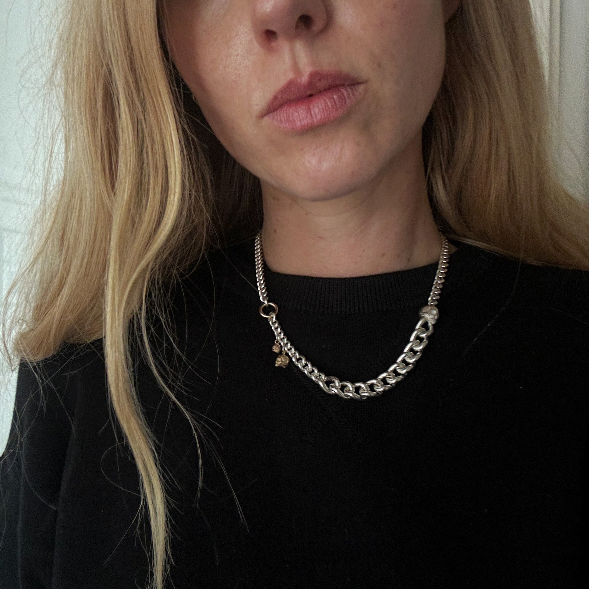 Heavy weight sterling silver curb link chain descending in size. 9ct yellow gold skulls hang off center from links. Handmade in London by Charlie Shires