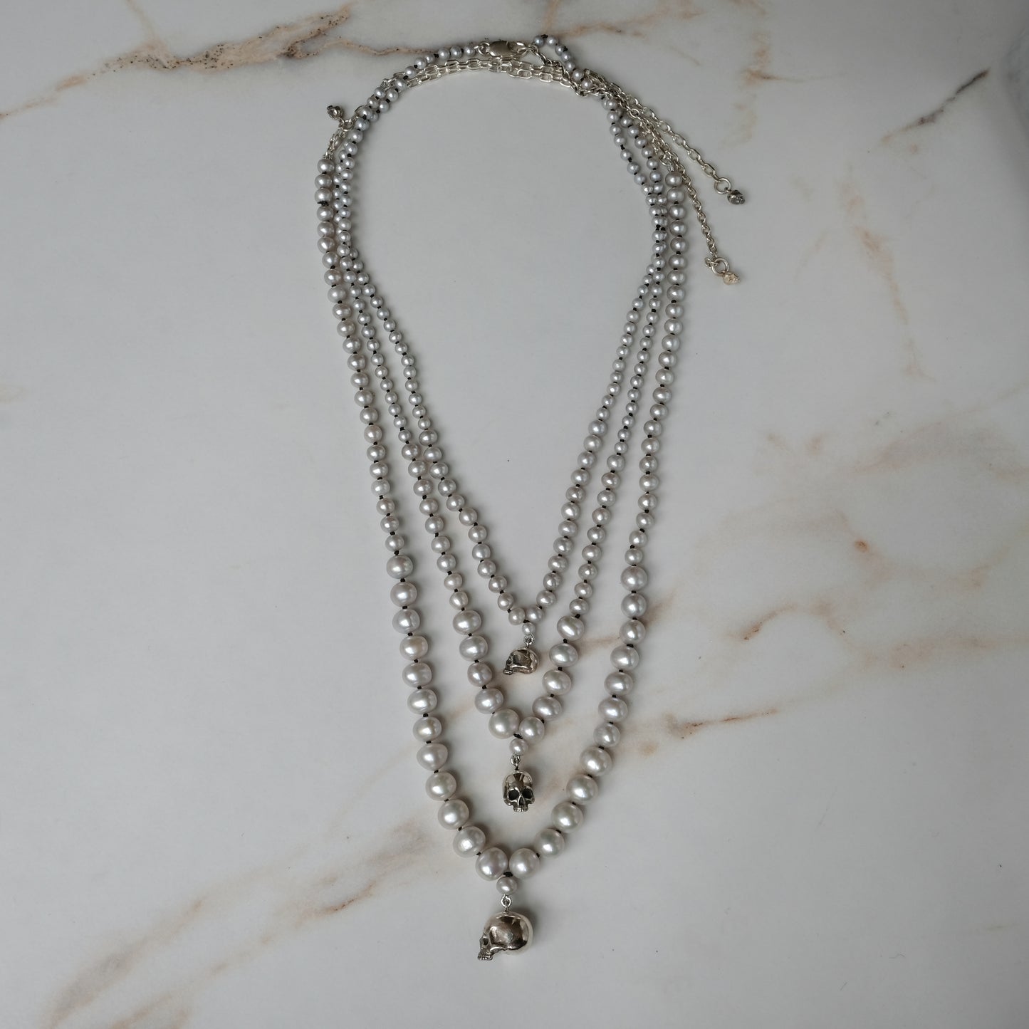 Hand strung grey freshwater pearls with a small, medium and large sterling silver skull, made by hand in London by Charlie Shires