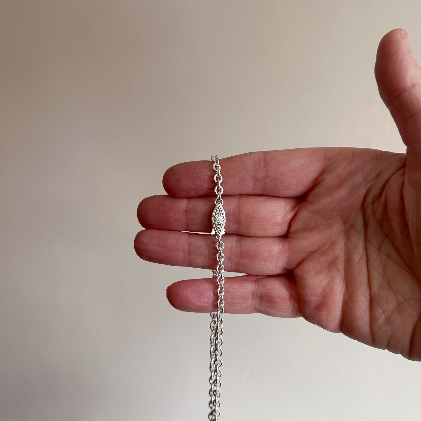 Hand carved crucifix necklace with pear shaped claw set drop black spinel. Made in sterling silver by Charlie Shires in London