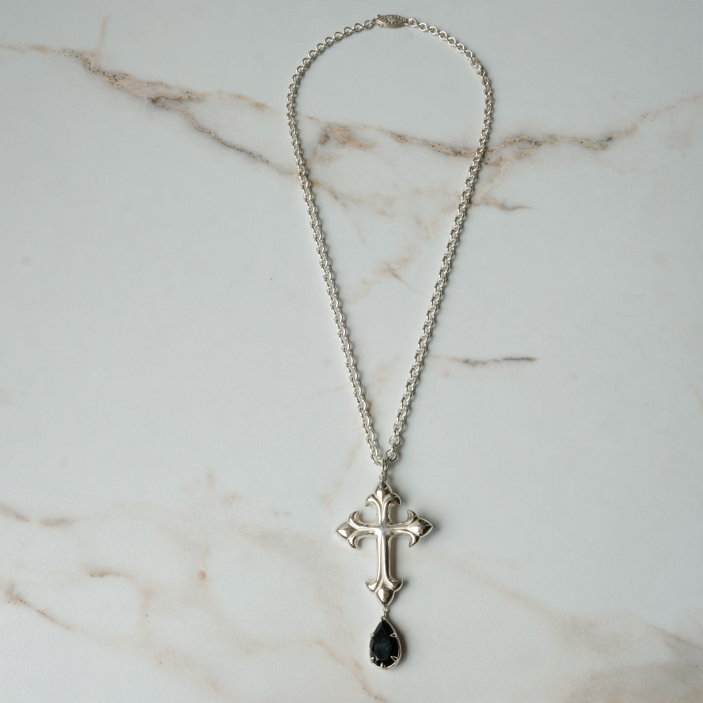 Hand carved crucifix necklace with pear shaped claw set drop black spinel. Made in sterling silver by Charlie Shires in London