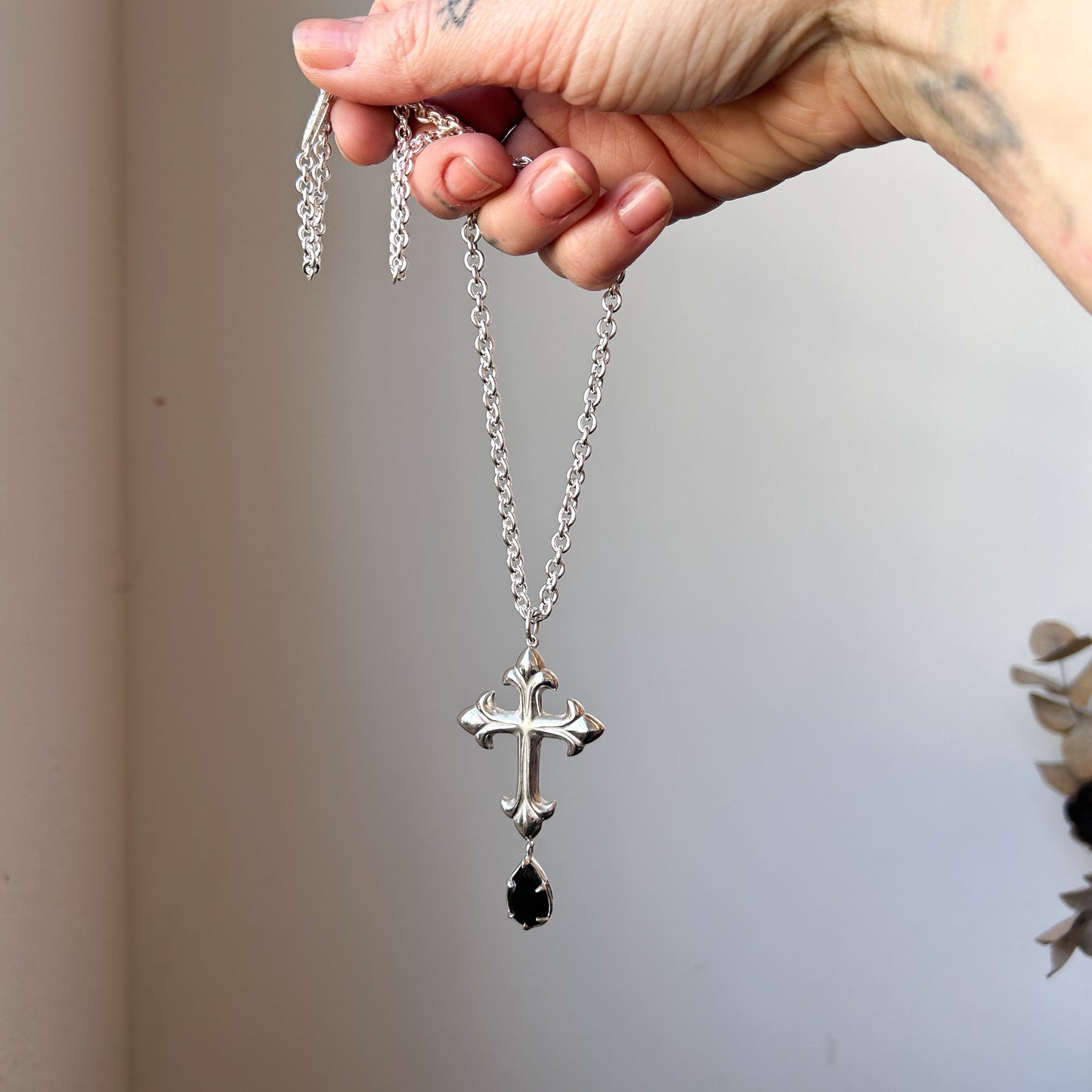 Hand carved crucifix necklace with pear shaped claw set drop black spinel. Made in sterling silver by Charlie Shires in London