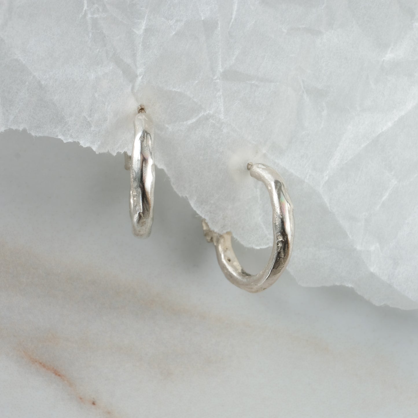 Small hoop earrings with molten detail and skulls at back in sterling silver by Charlie Shires