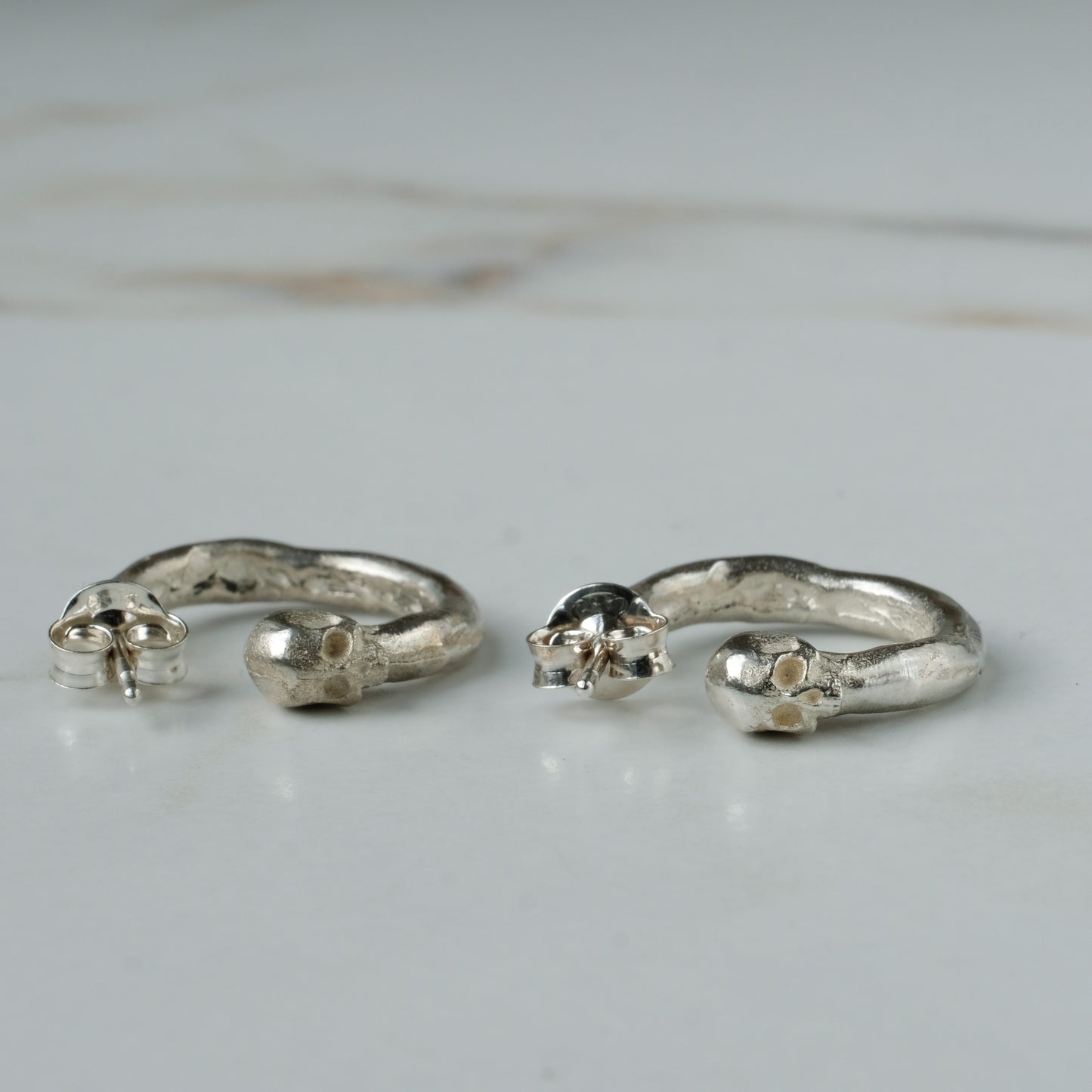 Small hoop earrings with molten detail and skulls at back in sterling silver by Charlie Shires