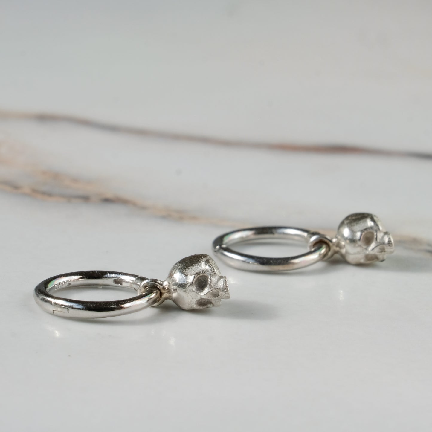 Sterling silver skull huggie hoop earrings made in London by Charlie Shires