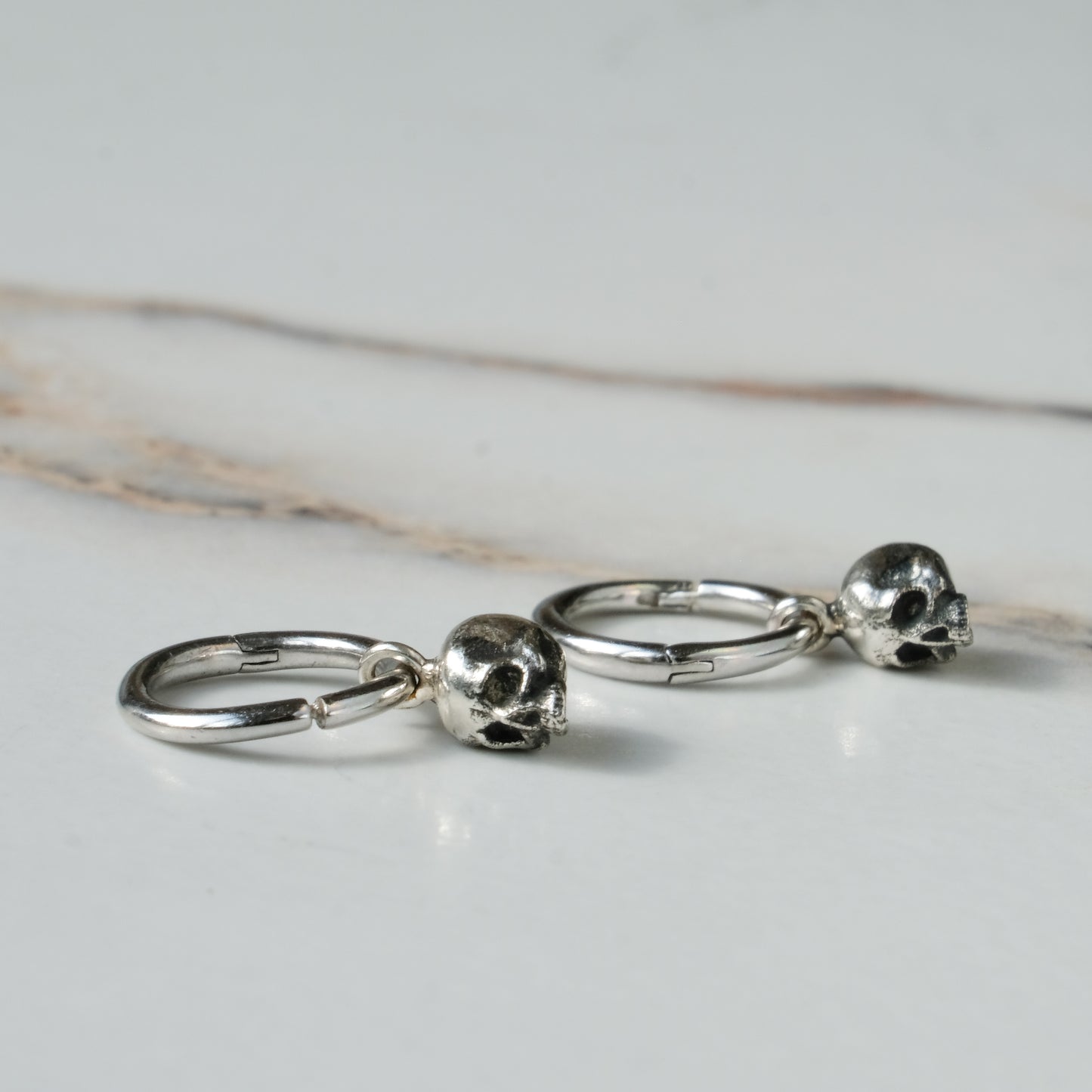 Sterling silver skull huggie hoop earrings made in London by Charlie Shires