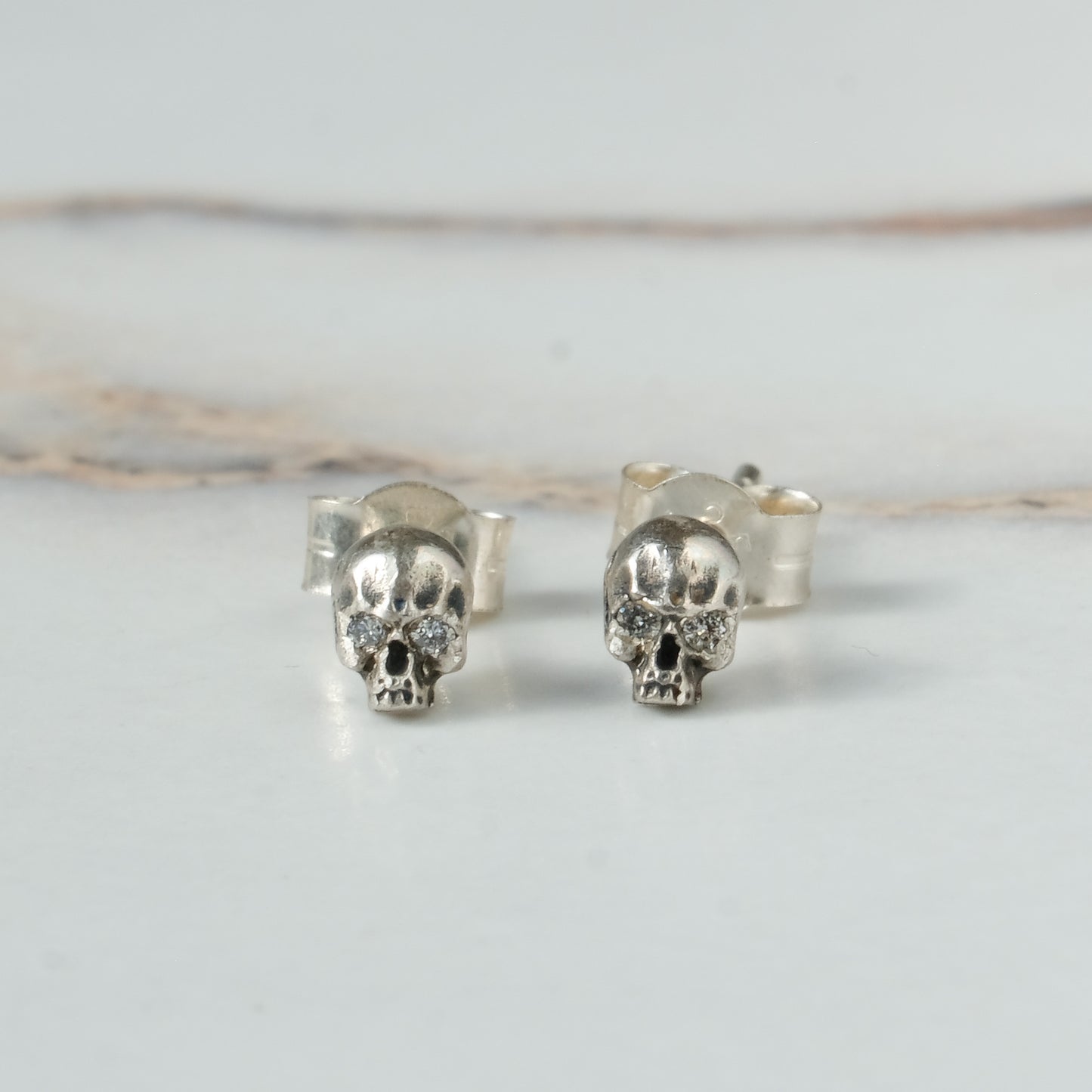 Small skull studs with diamonds made in sterling silver in London by Charlie Shires