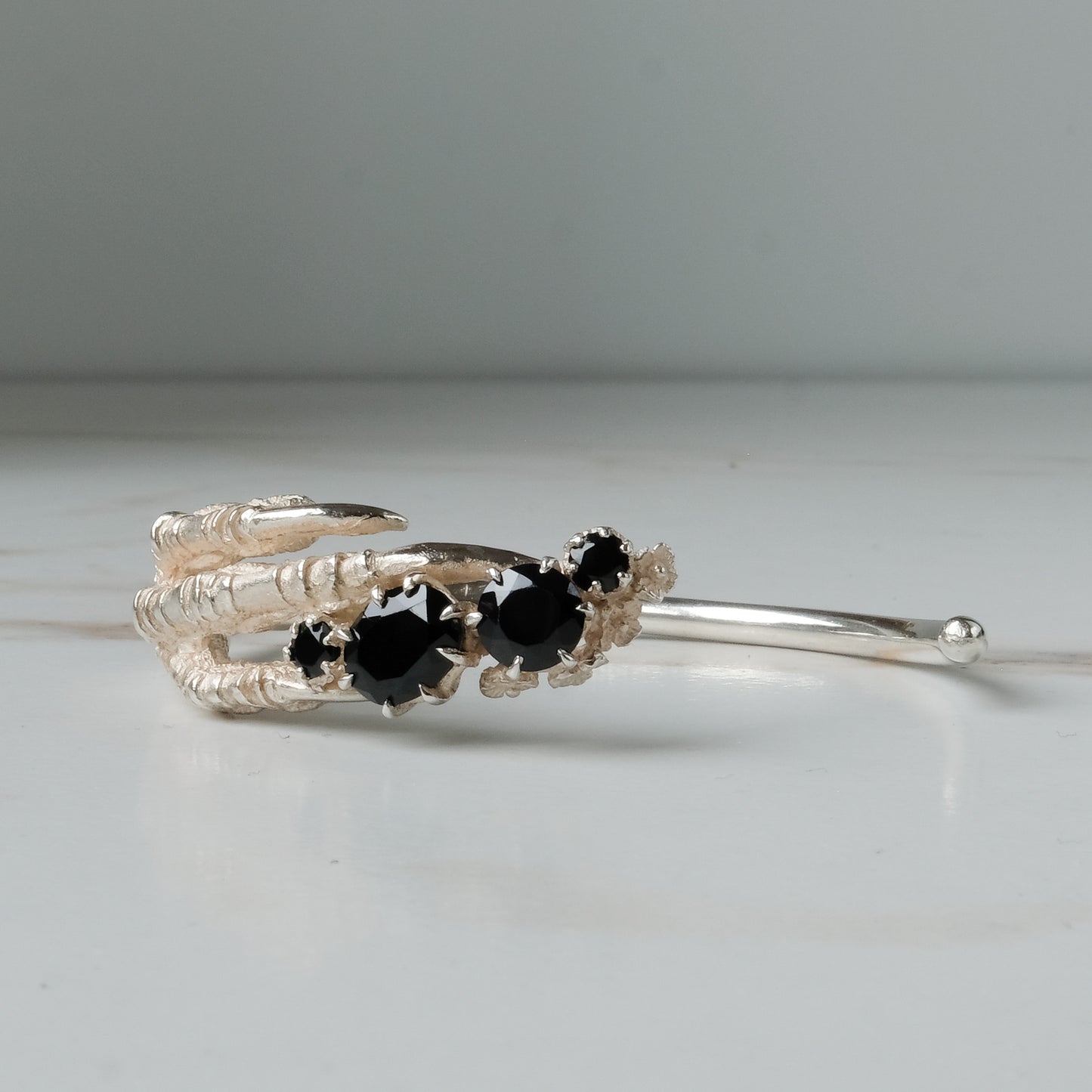 Sterling silver birds claw talon bangle handmade with black spinel stones and flowers in London by Charlie Shires
