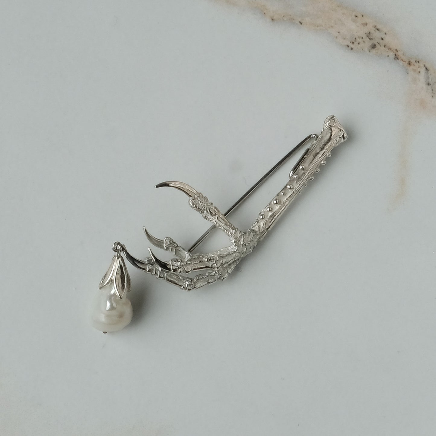 Birds claw talon brooch made in sterling silver with drop freshwater pearl. Made in London by Charlie Shires