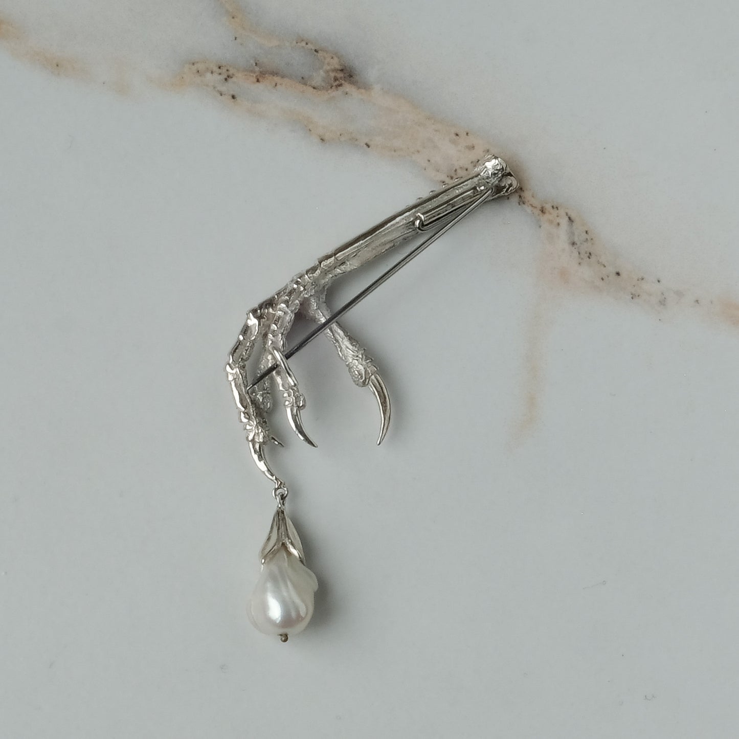 Birds claw talon brooch made in sterling silver with drop freshwater pearl. Made in London by Charlie Shires