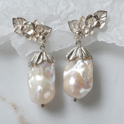 Silver stud earrings with skulls, flowers and baroque pearls. Made in recycled silver in London by Charlie Shires