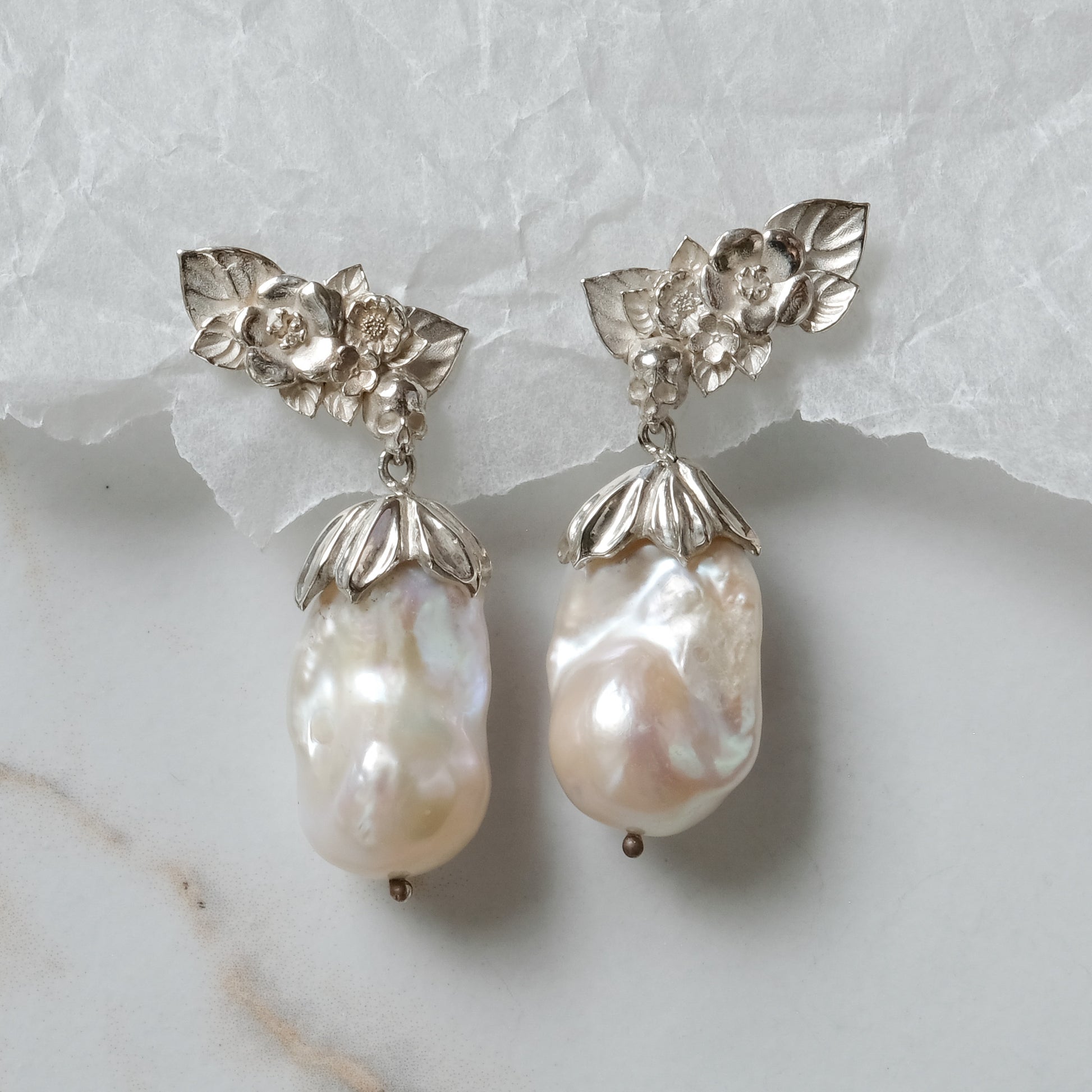 Silver stud earrings with skulls, flowers and baroque pearls. Made in recycled silver in London by Charlie Shires