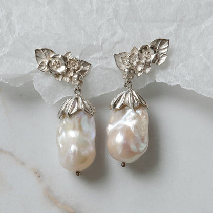 Silver stud earrings with skulls, flowers and baroque pearls. Made in recycled silver in London by Charlie Shires