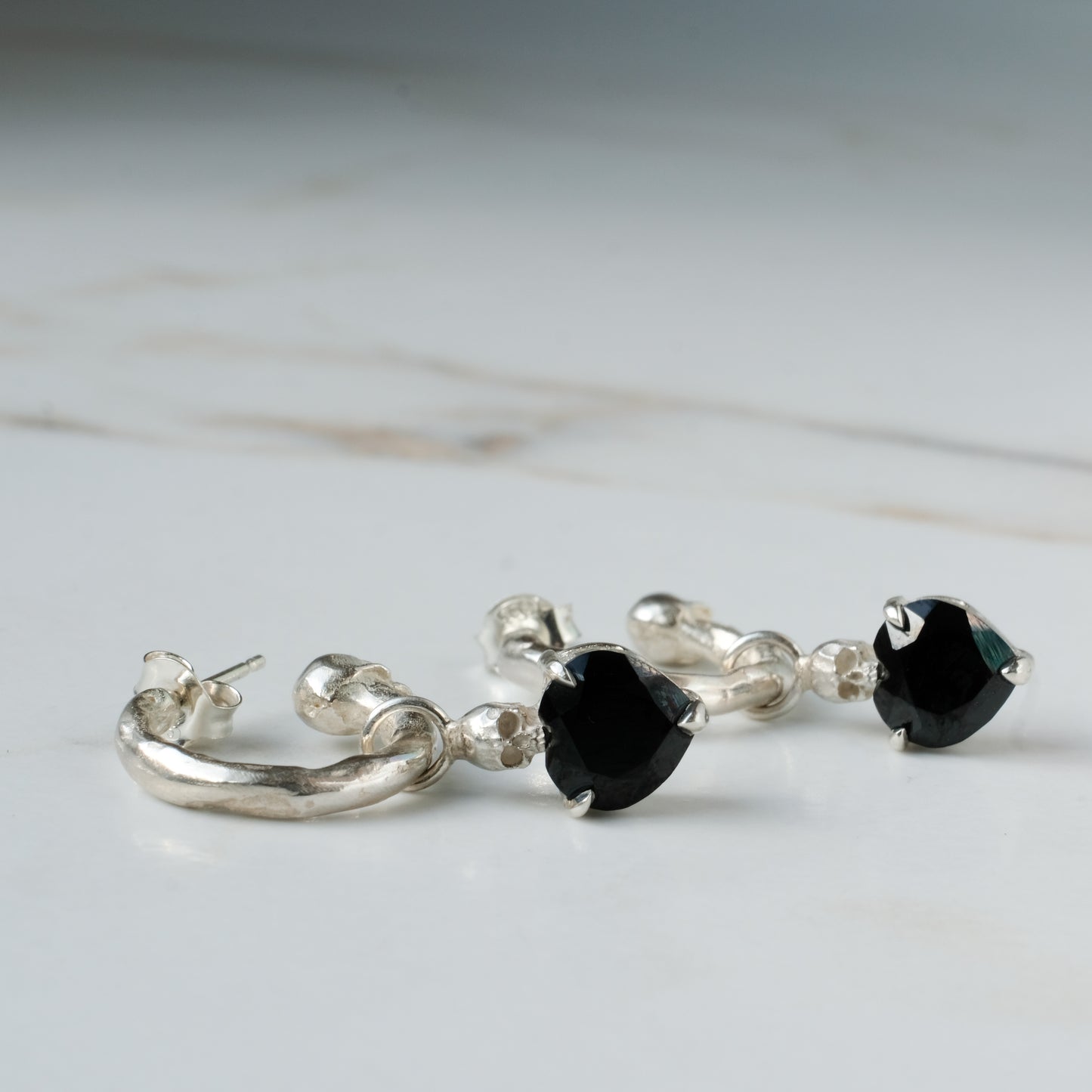 Sterling silver Annie molten hoops with drop black spinel hearts and skulls. Made in London by Charlie Shires