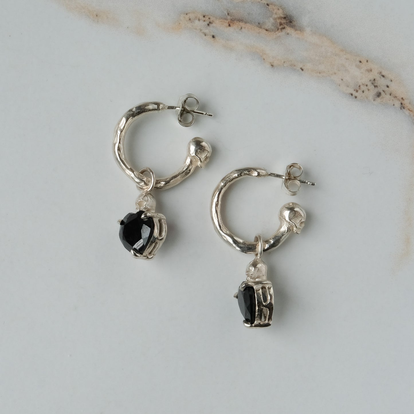 Sterling silver Annie molten hoops with drop black spinel hearts and skulls. Made in London by Charlie Shires
