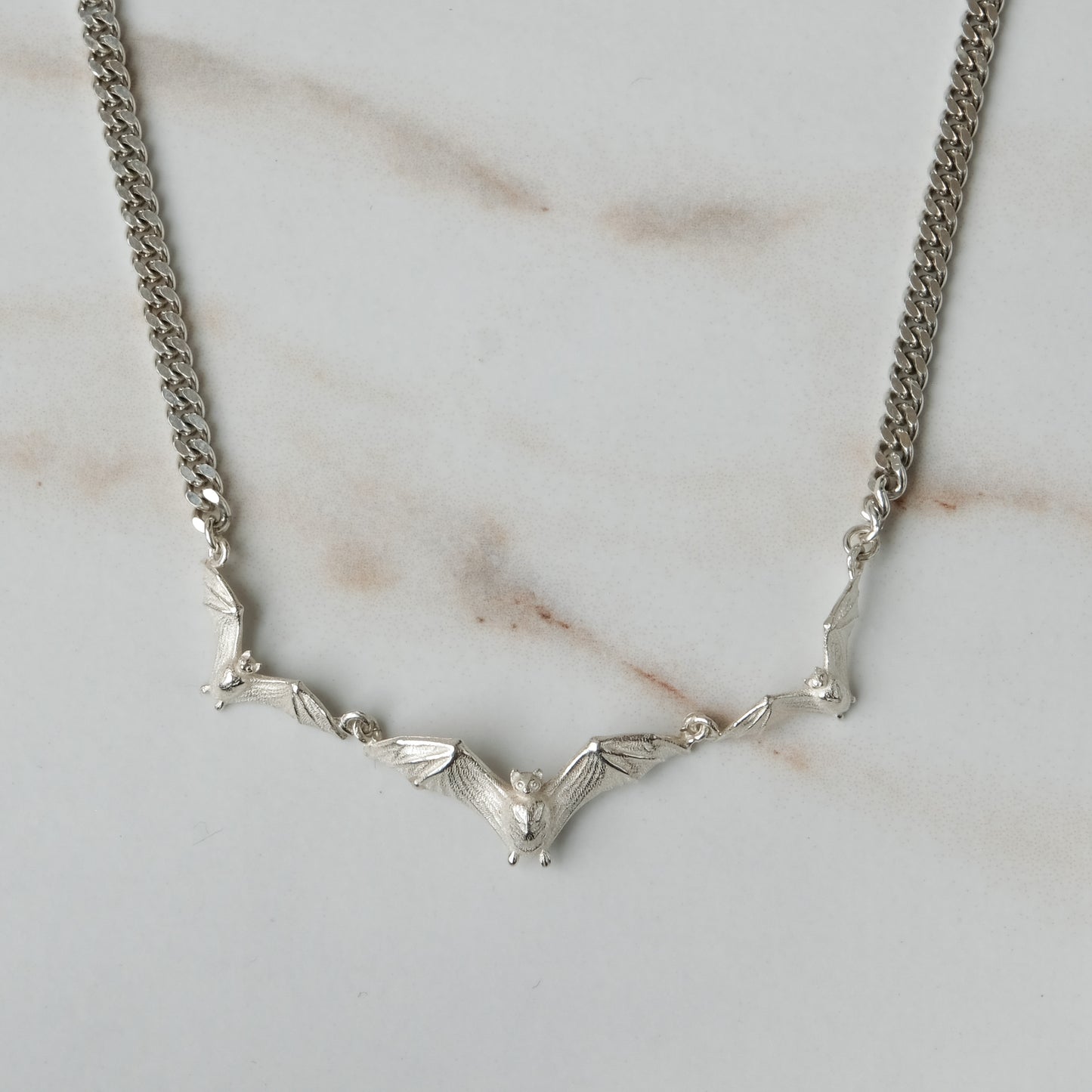 Three bat necklace on curb link chain, made in sterling silver by Charlie Shires in London
