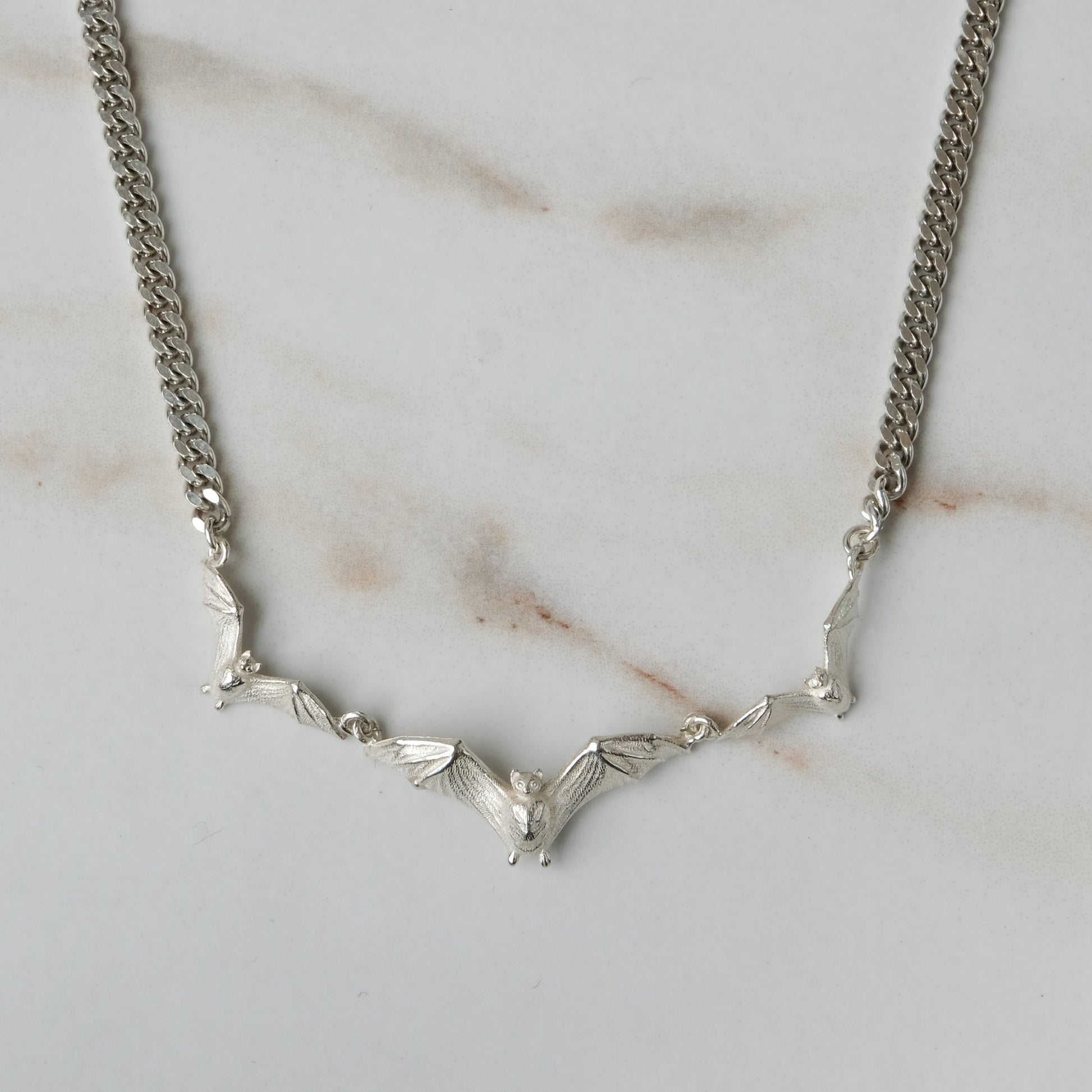 Three bat necklace on curb link chain, made in sterling silver by Charlie Shires in London