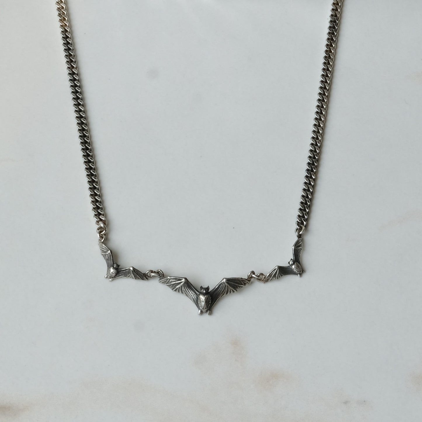 Three bat necklace on curb link chain, made in sterling silver by Charlie Shires in London