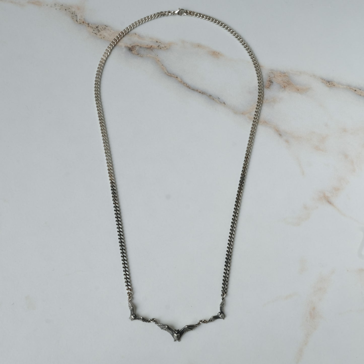 Three bat necklace on curb link chain, made in sterling silver by Charlie Shires in London