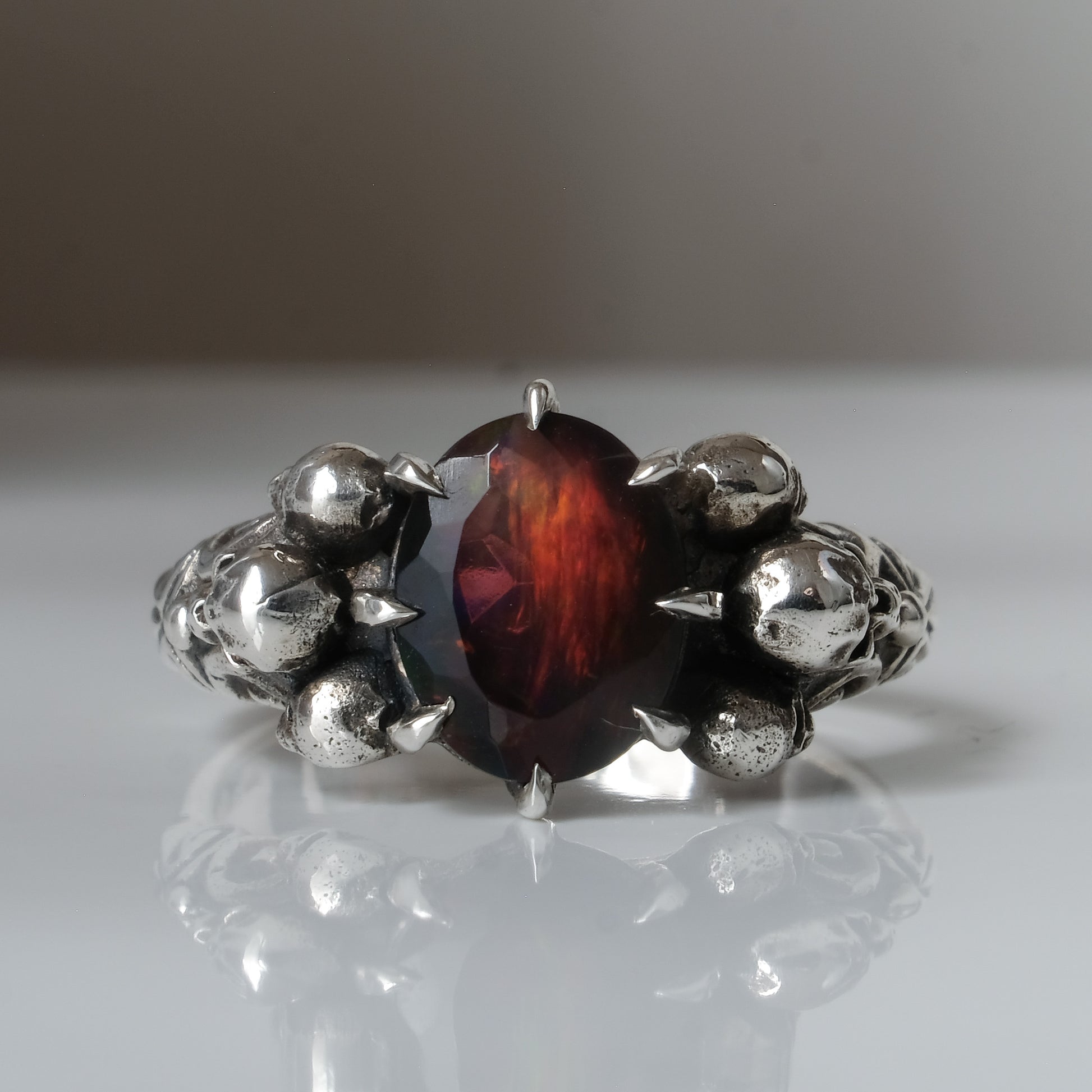 Three skull ring with central black opal and decorative band by Charlie Shires