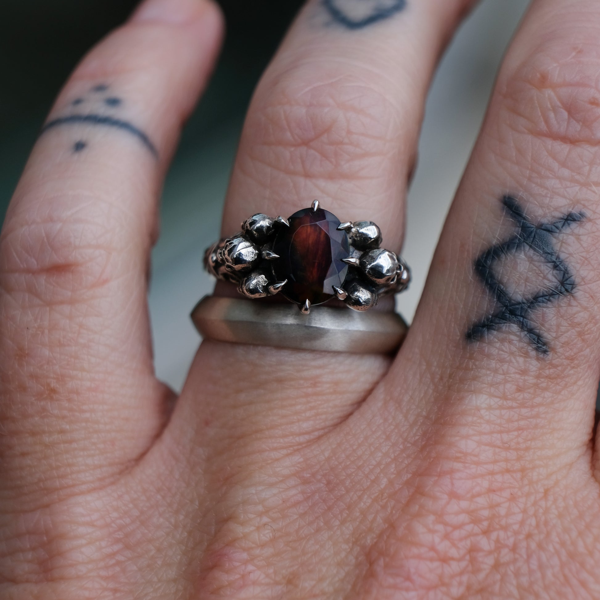 Three skull ring with central black opal and decorative band by Charlie Shires