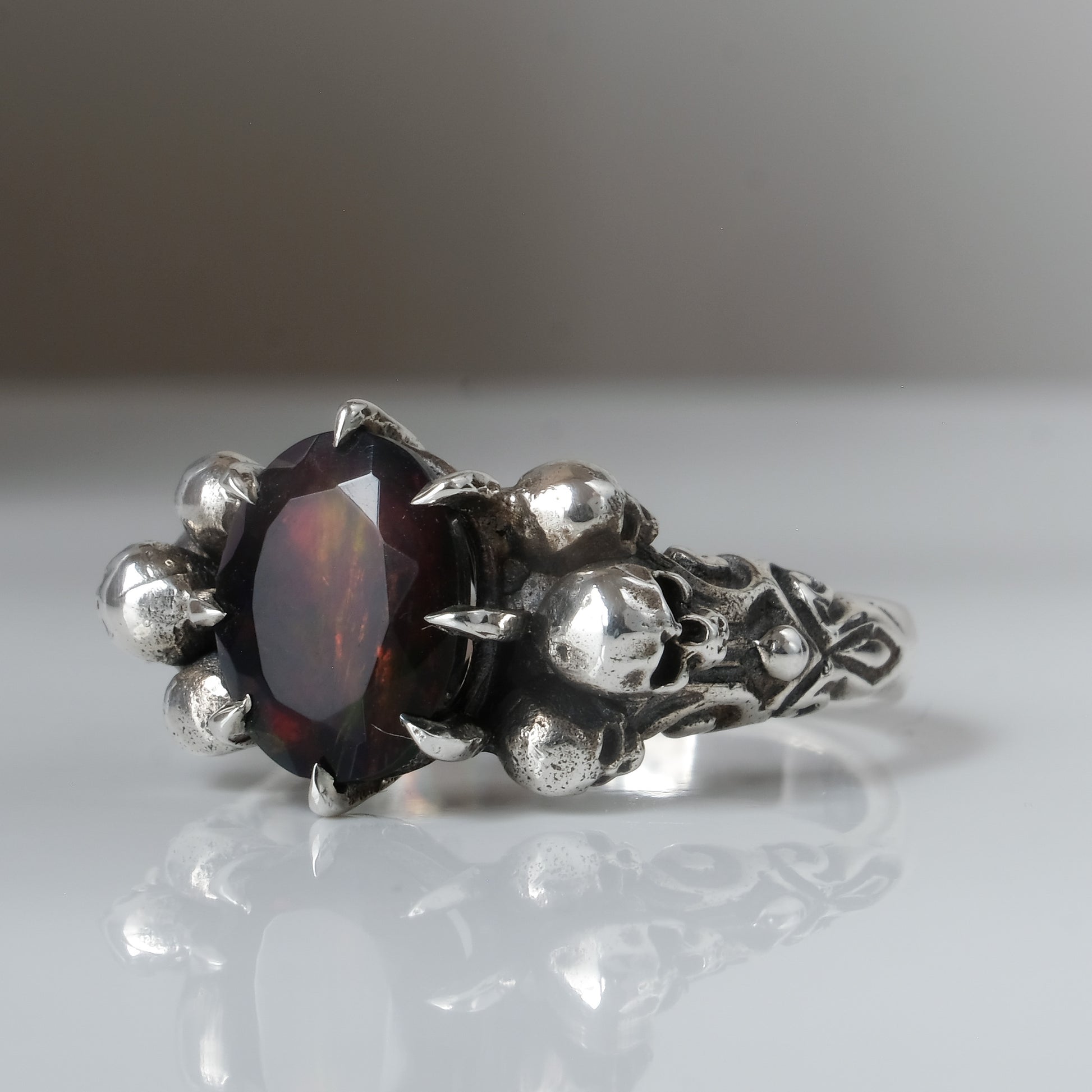 Three skull ring with central black opal and decorative band by Charlie Shires