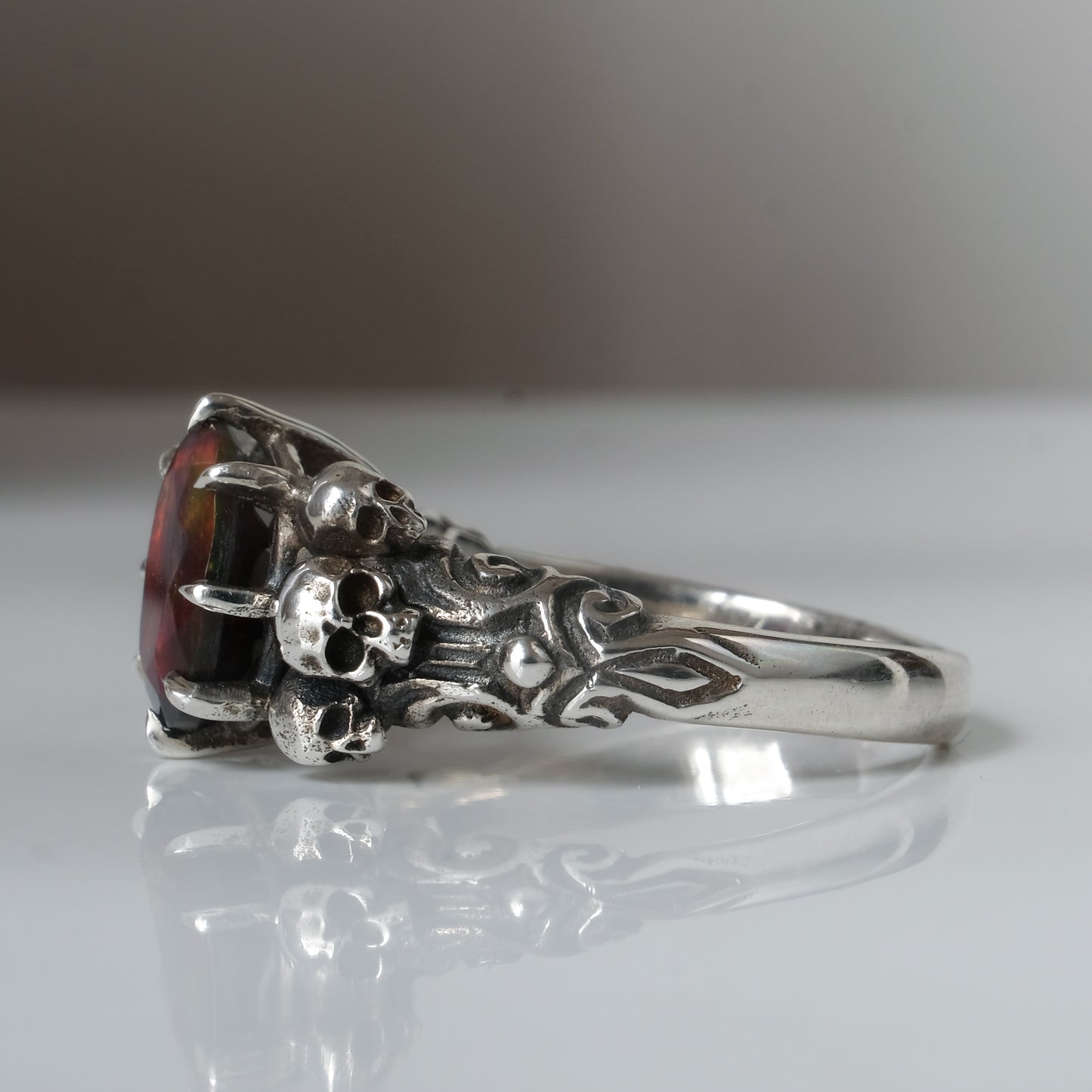 Three skull ring with central black opal and decorative band by Charlie Shires