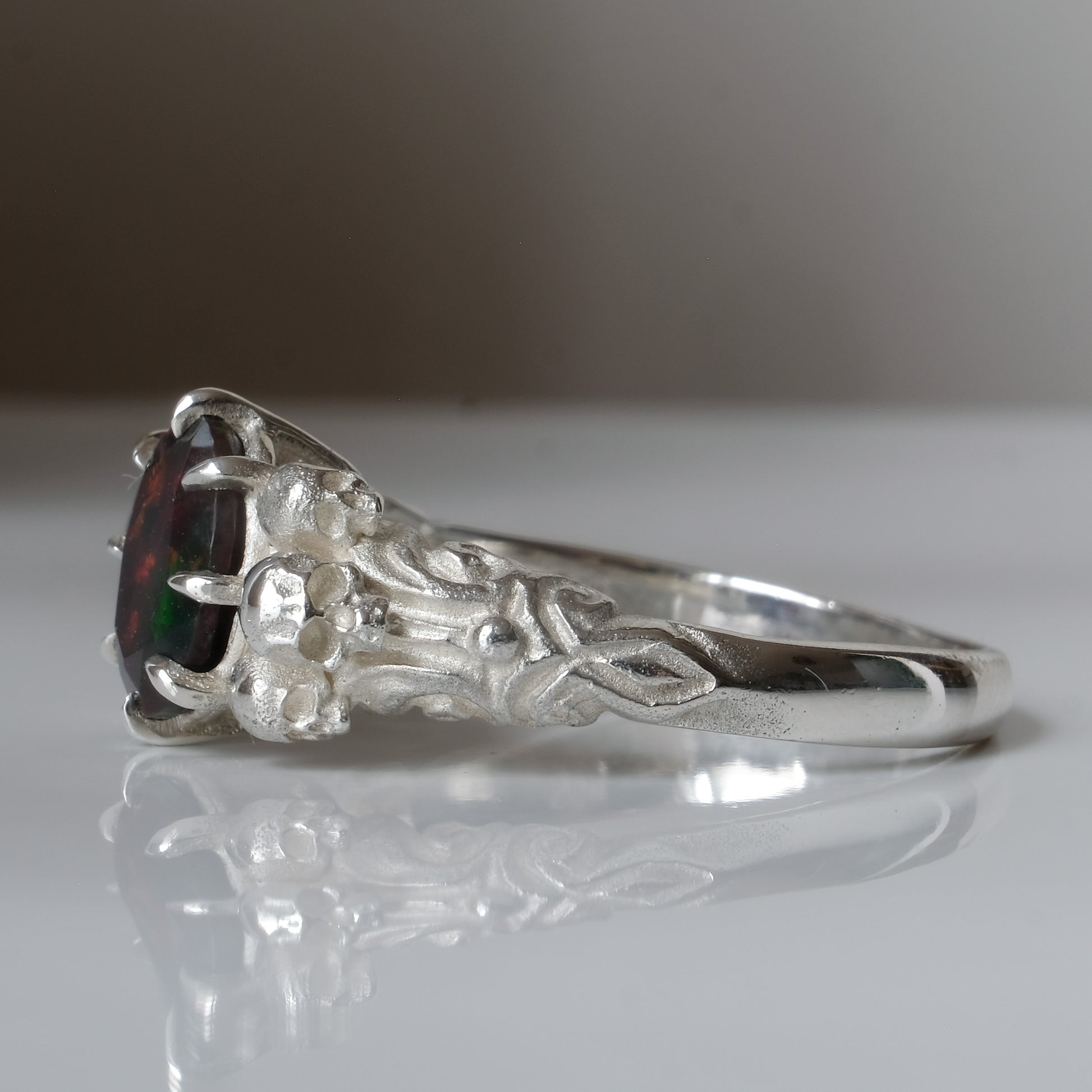 Three skull ring with central black opal and decorative band by Charlie Shires