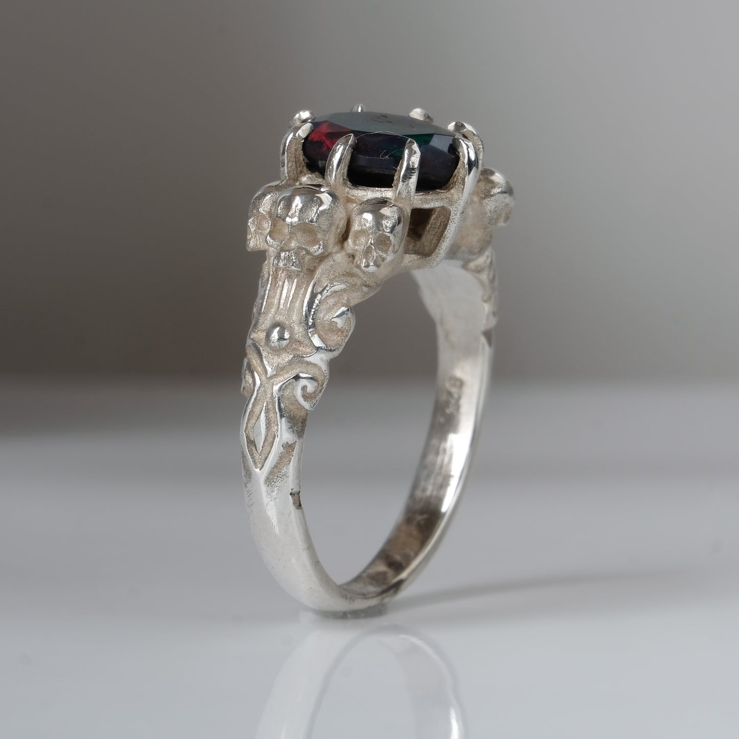 Three skull ring with central black opal and decorative band by Charlie Shires