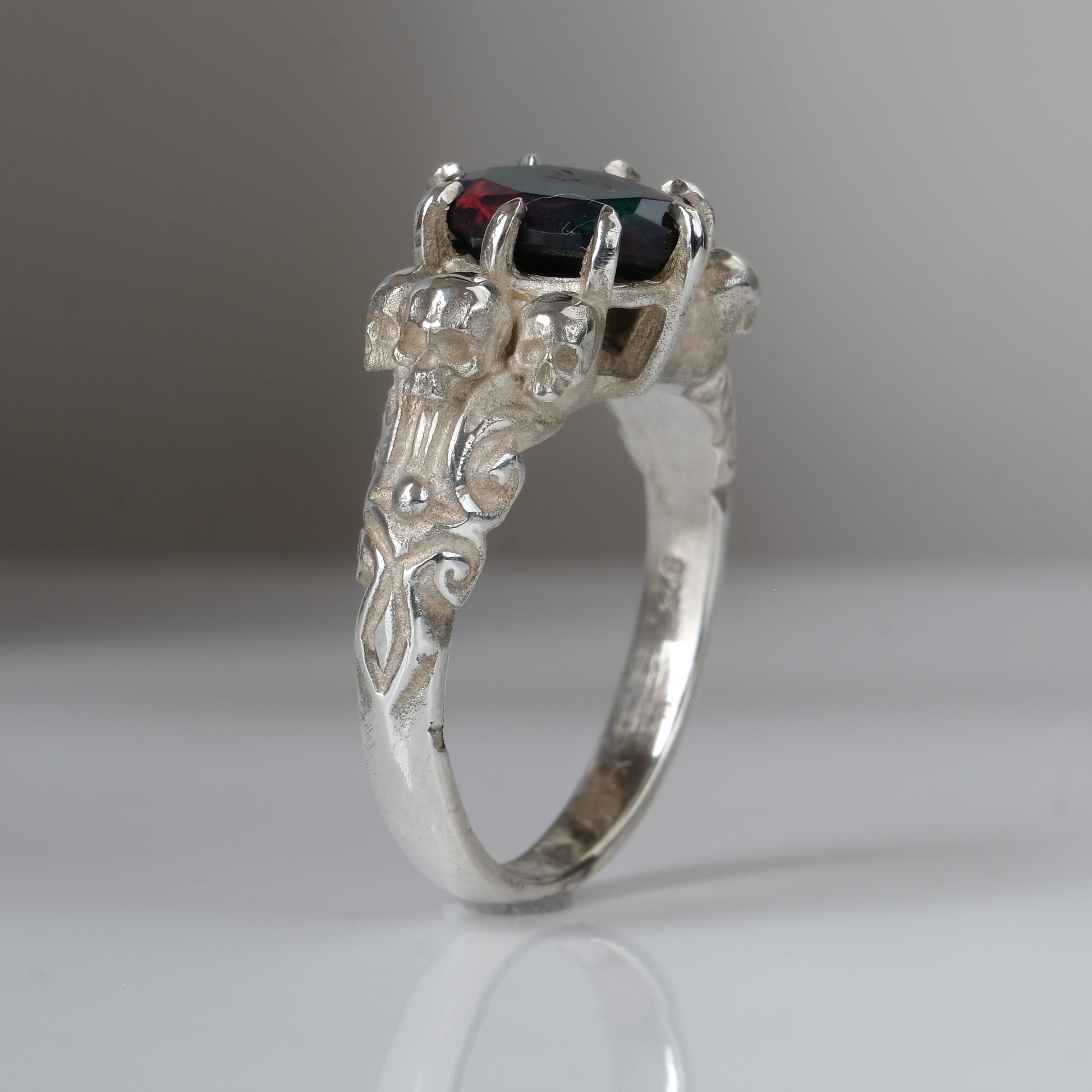 Three skull ring with central black opal and decorative band by Charlie Shires