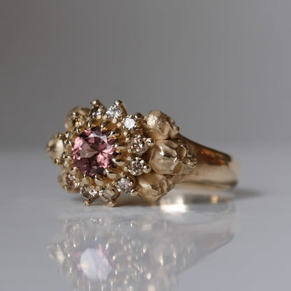 9ct yellow gold engagement ring with central colour change garnet and a champagne diamond halo. 6 skulls flank the side of the setting. 
Handmade in London by Charlie Shires