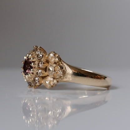 9ct yellow gold engagement ring with central colour change garnet and a champagne diamond halo. 6 skulls flank the side of the setting. 
Handmade in London by Charlie Shires