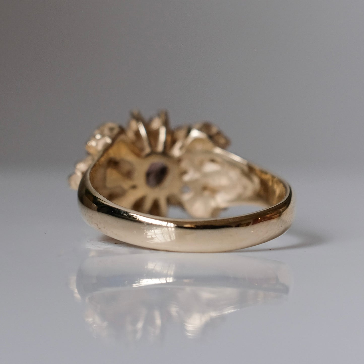 9ct yellow gold engagement ring with central colour change garnet and a champagne diamond halo. 6 skulls flank the side of the setting. 
Handmade in London by Charlie Shires