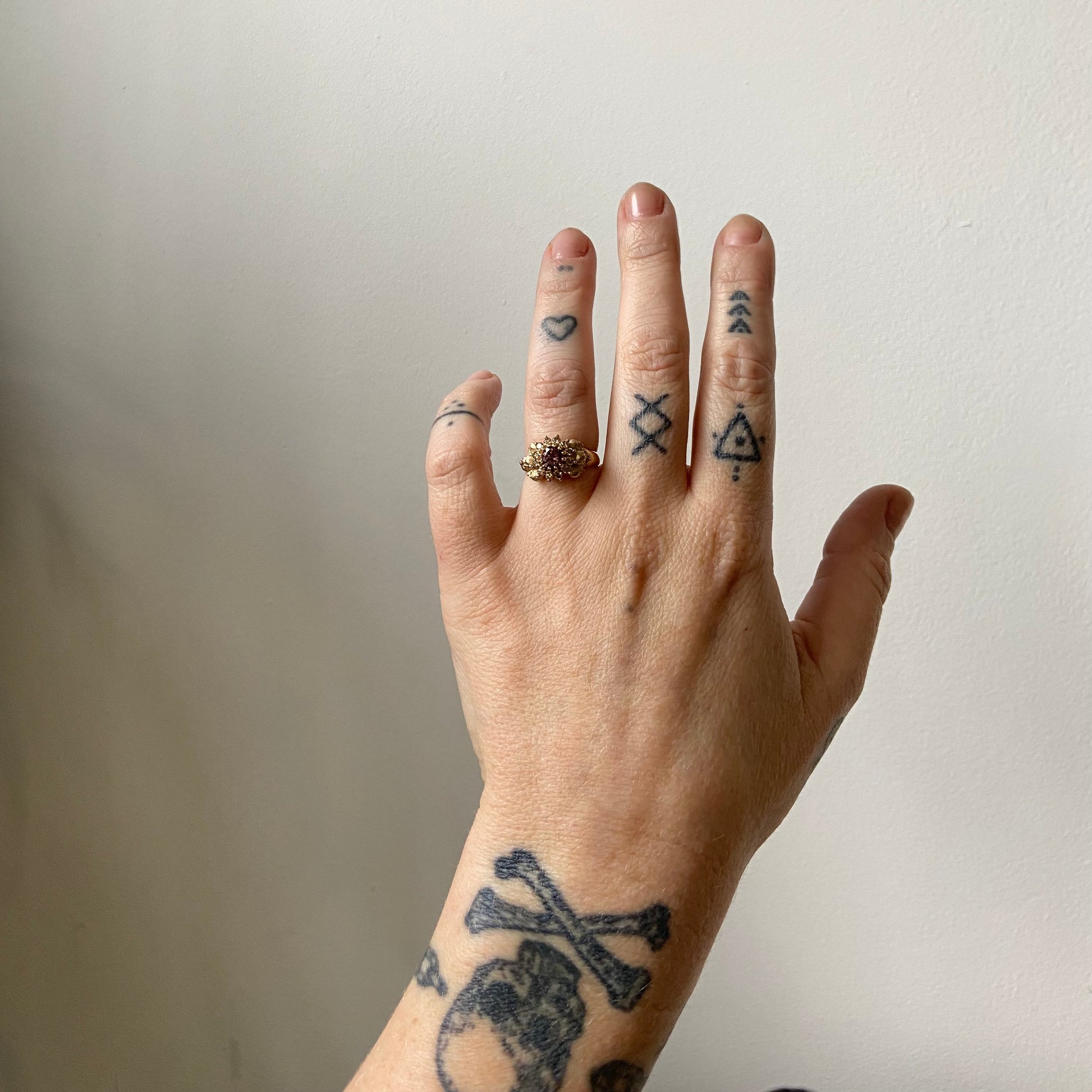 9ct yellow gold engagement ring with central colour change garnet and a champagne diamond halo. 6 skulls flank the side of the setting. 
Handmade in London by Charlie Shires