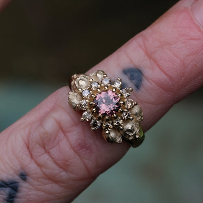 9ct yellow gold engagement ring with central colour change garnet and a champagne diamond halo. 6 skulls flank the side of the setting. 
Handmade in London by Charlie Shires
