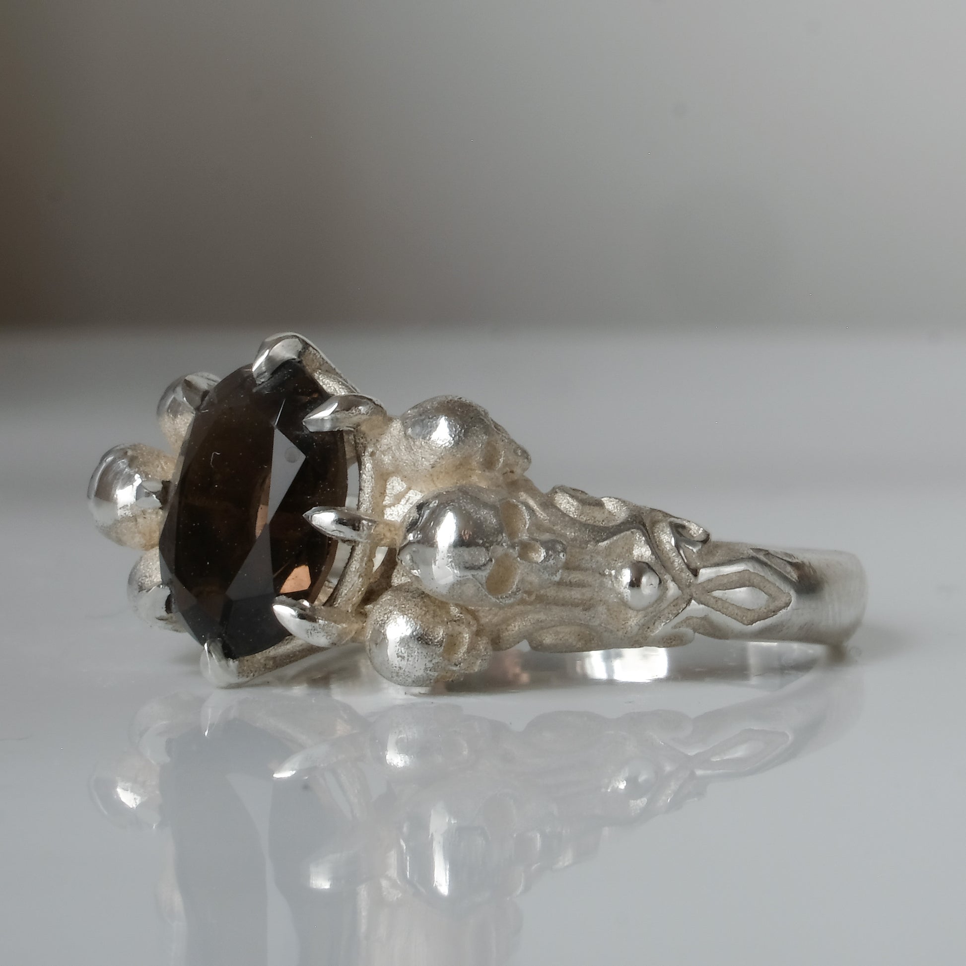 Three skull ring with central tourmaline and decorative band