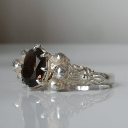 Three skull ring with central tourmaline and decorative band