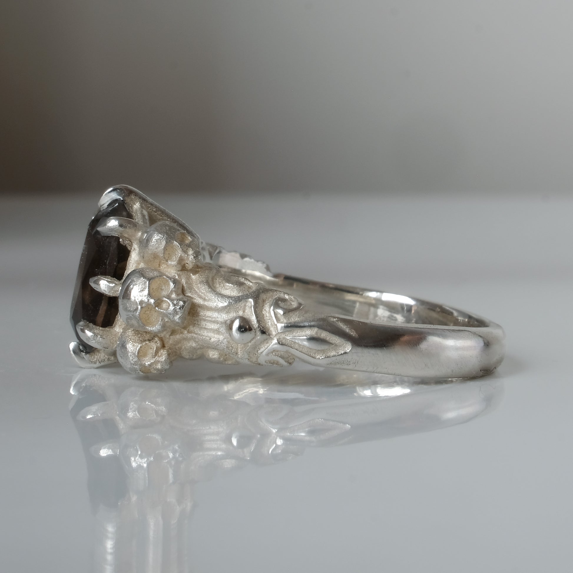 Three skull ring with central tourmaline and decorative band