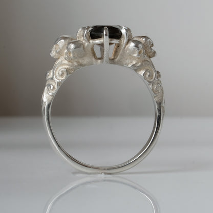 Three skull ring with central tourmaline and decorative band