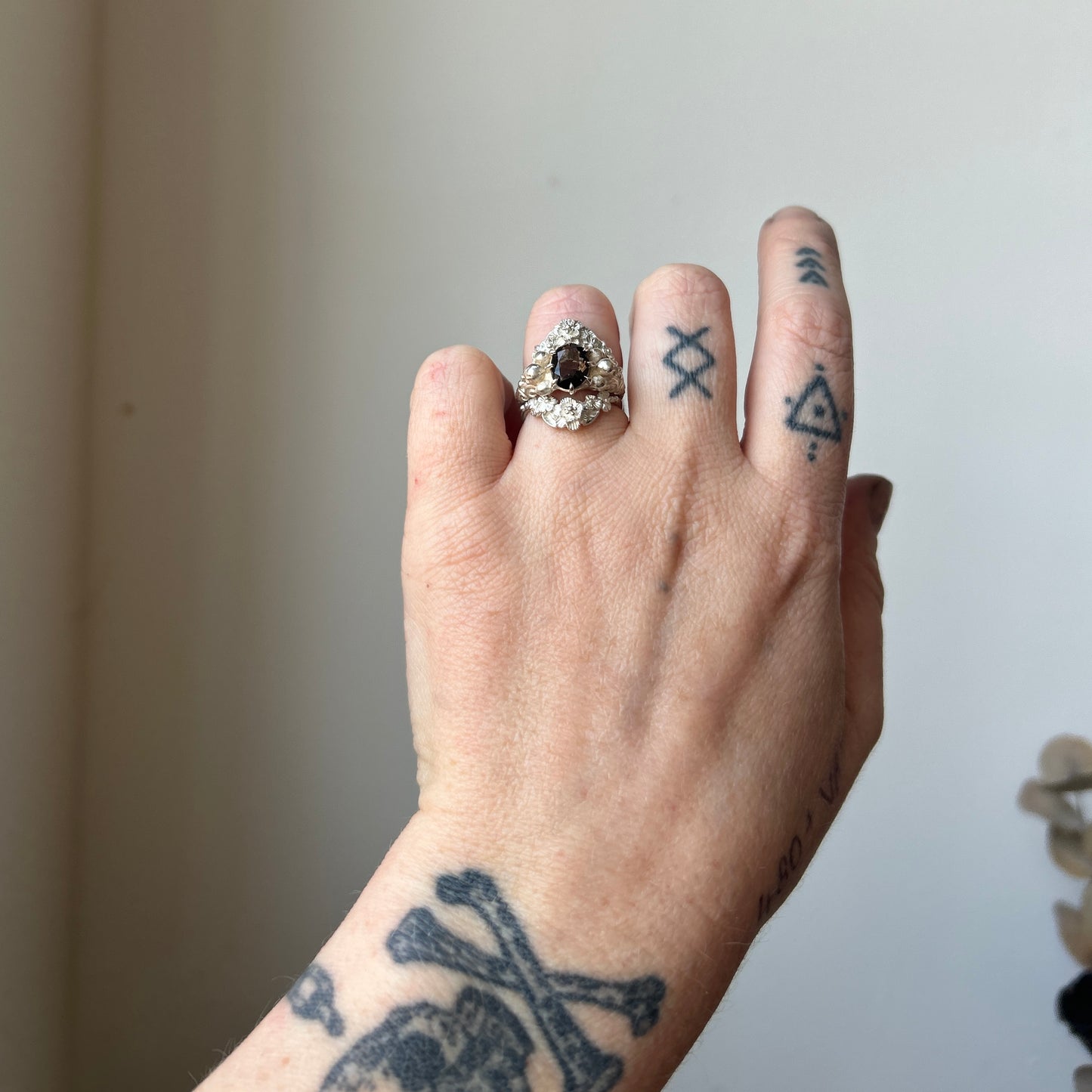 Three skull ring with central tourmaline and decorative band stacked with wreath II floral stack rings in sterling silver