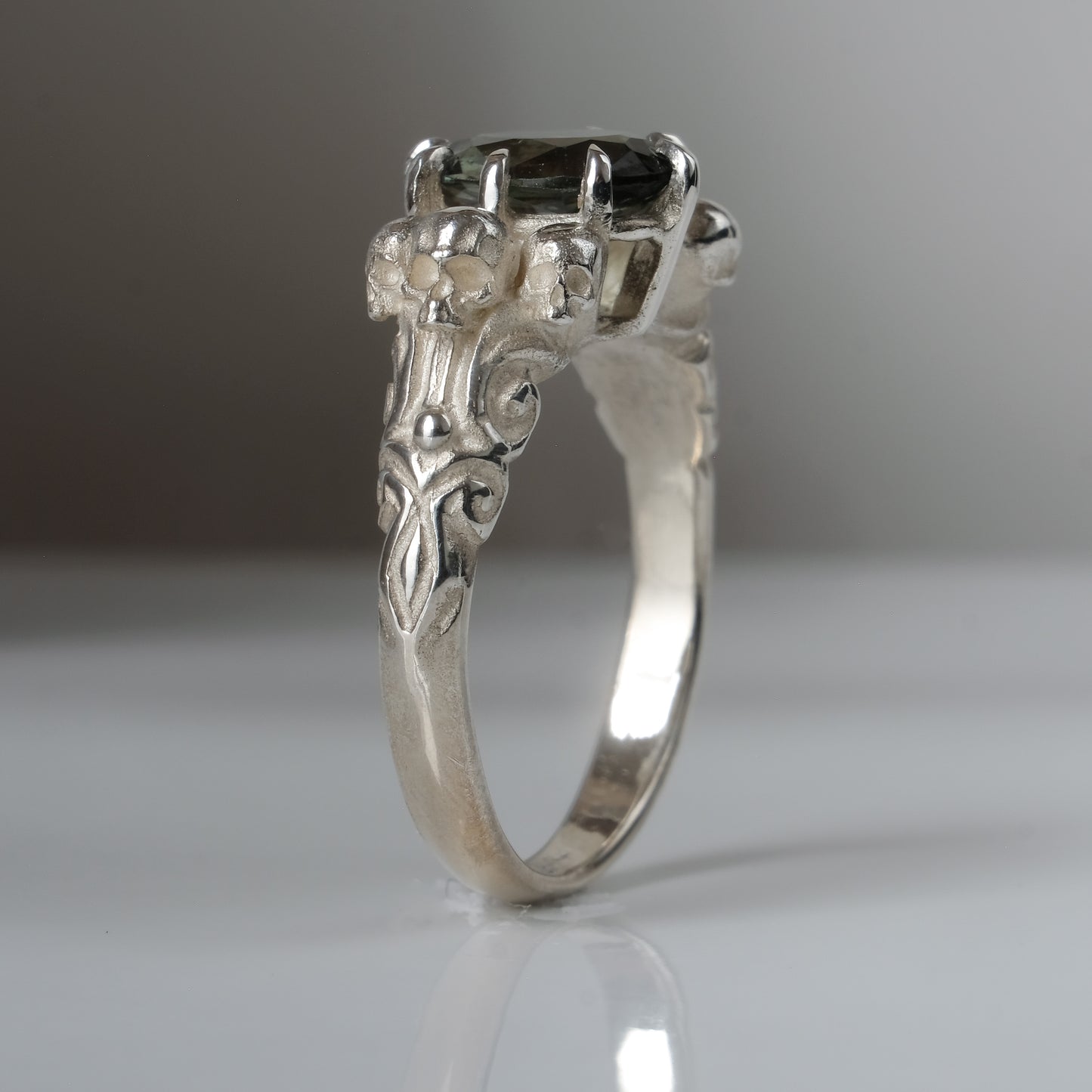 Three skull ring with central tourmaline and decorative band