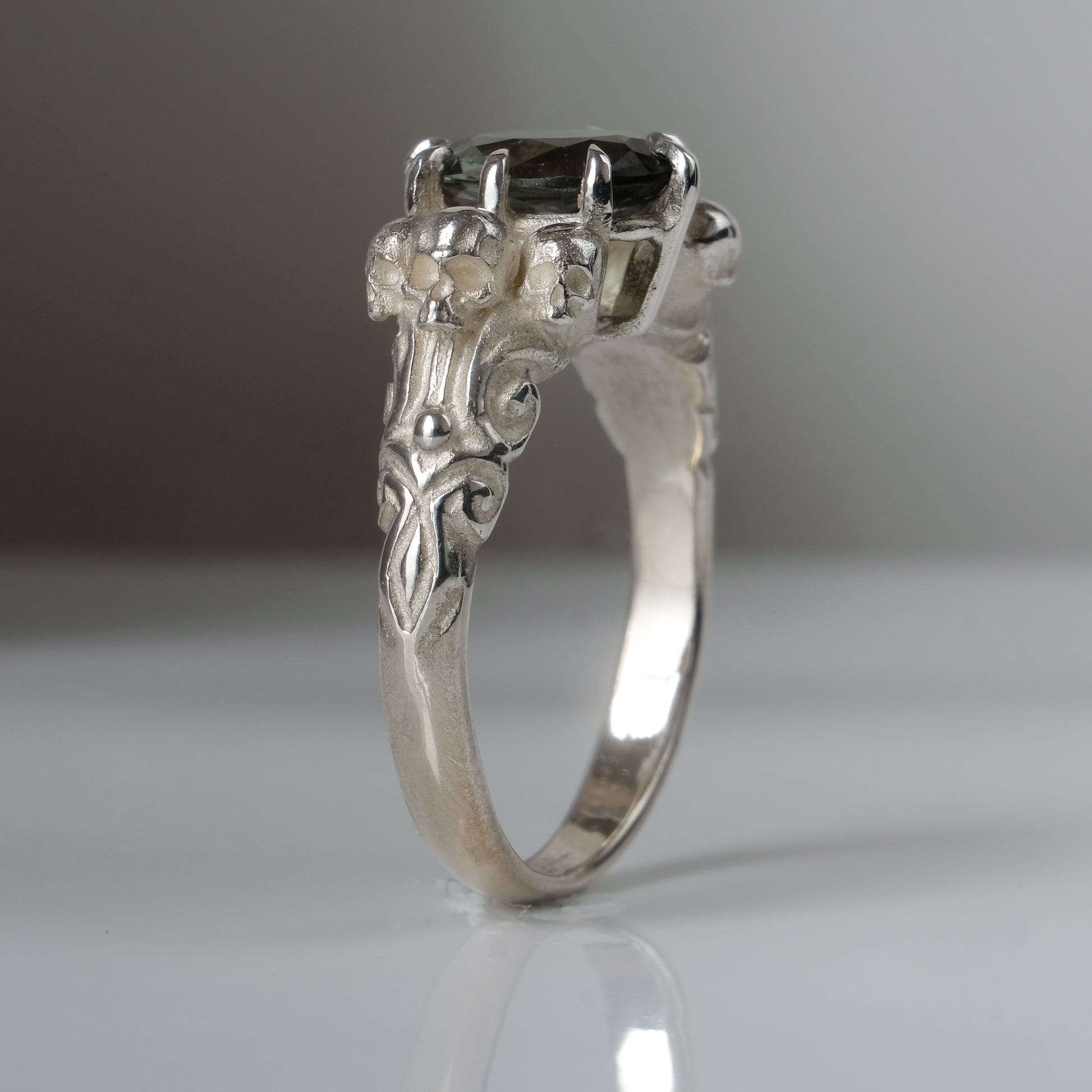 Three skull ring with central tourmaline and decorative band