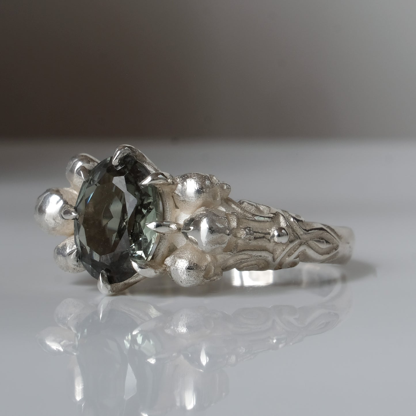 Three skull ring with central tourmaline and decorative band