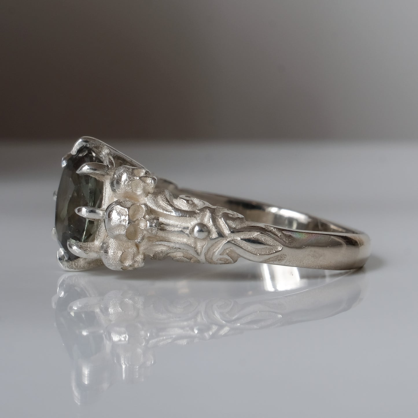 Three skull ring with central tourmaline and decorative band