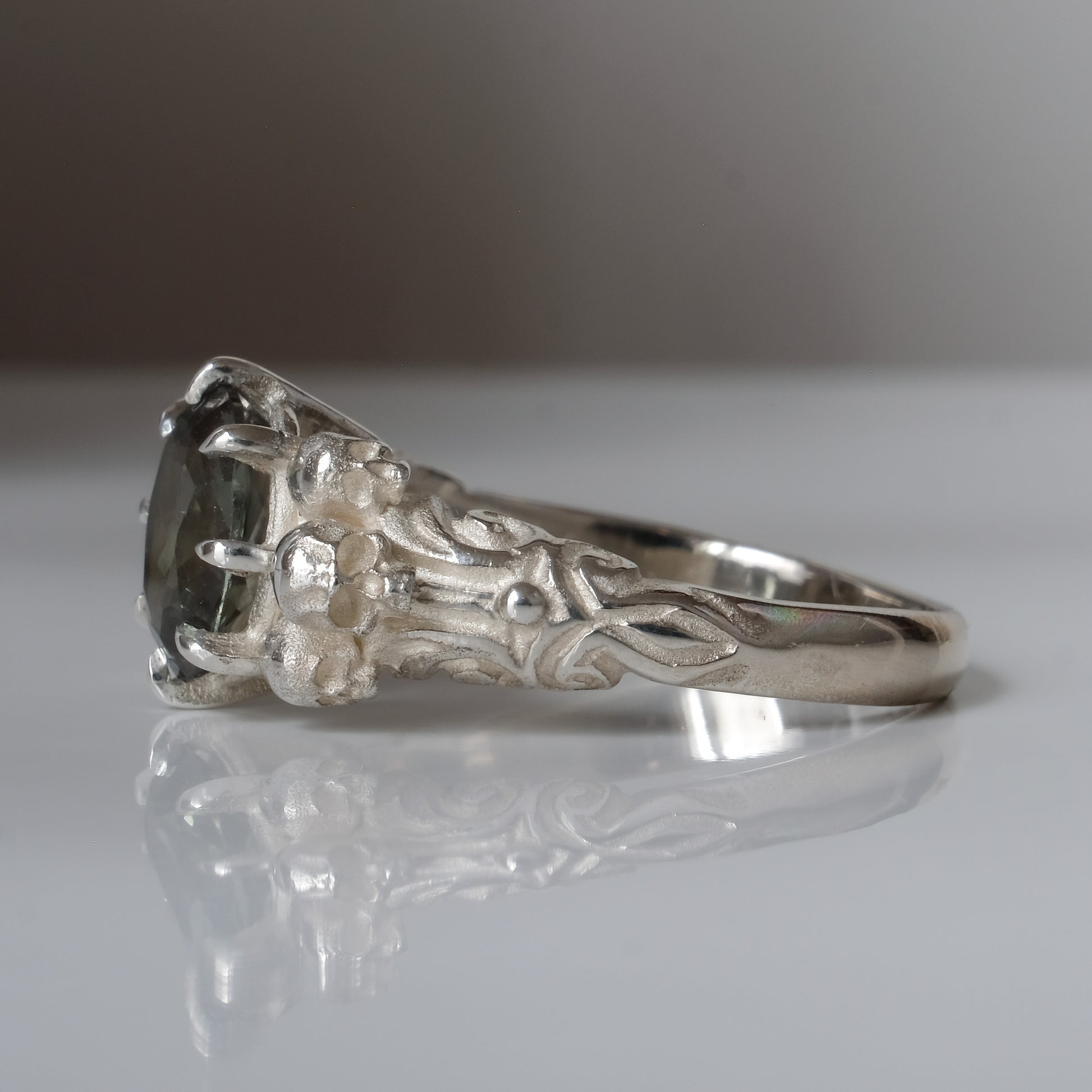 Three skull ring with central tourmaline and decorative band