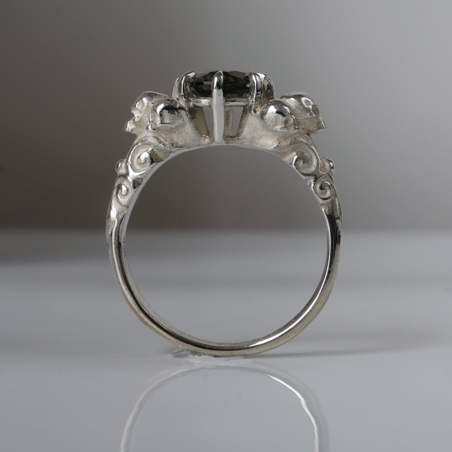 Three skull ring with central tourmaline and decorative band