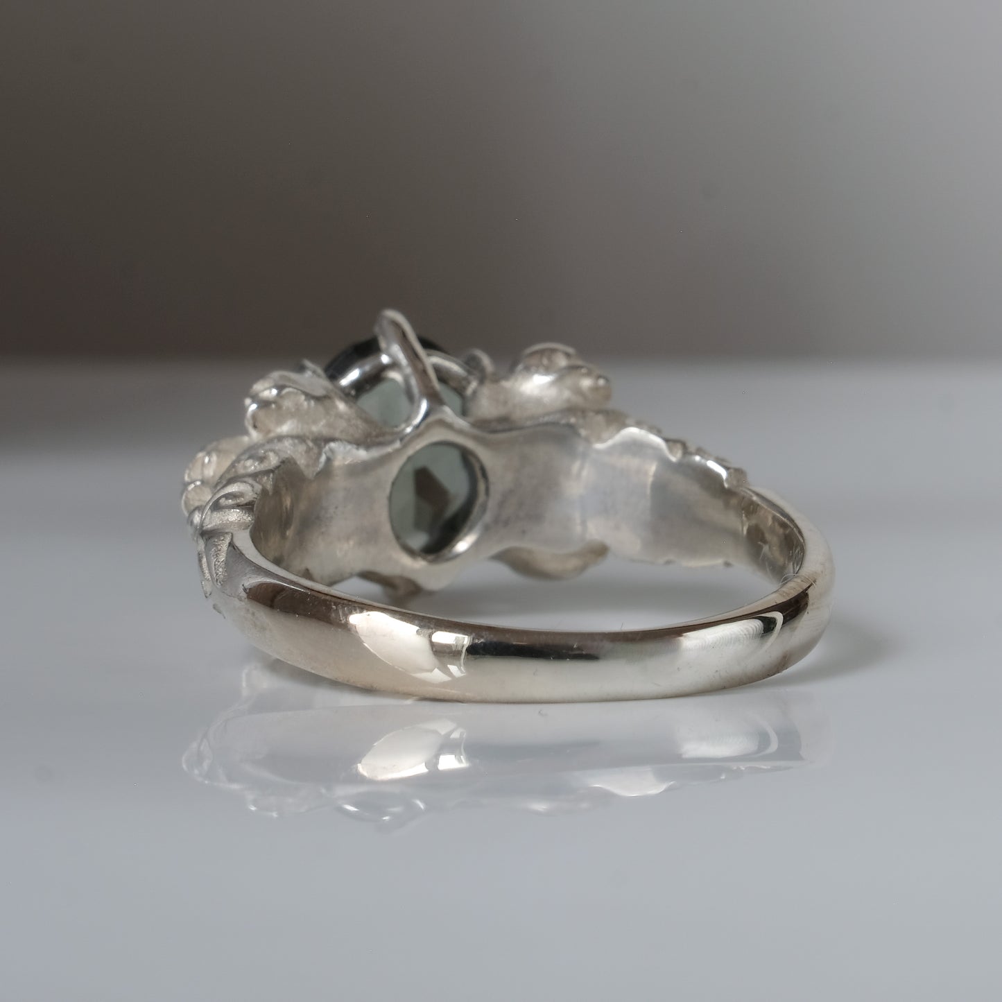 Three skull ring with central tourmaline and decorative band