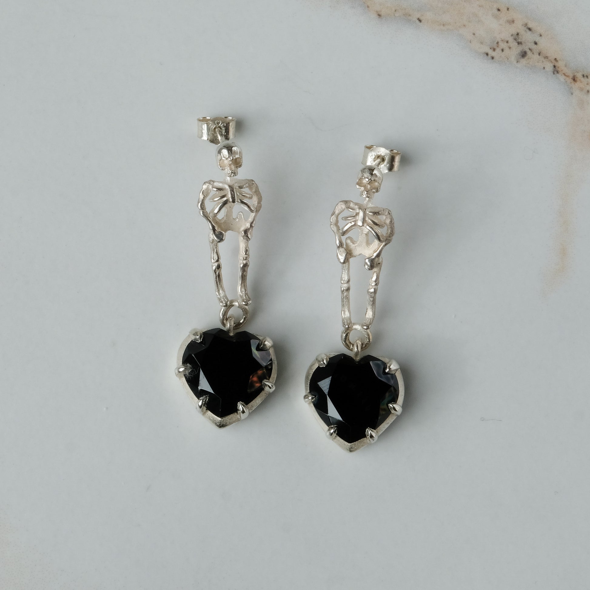 Skeleton earrings with black spinel heart shaped stones made in sterling silver in London by Charlie Shires
