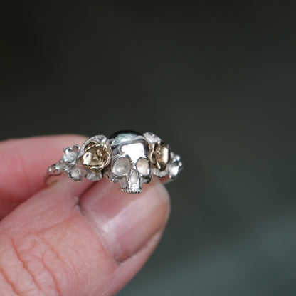Sterling silver ring with central skull and 9ct yellow gold flower and leaves cascading down band. Handmade in London by Charlie Shires