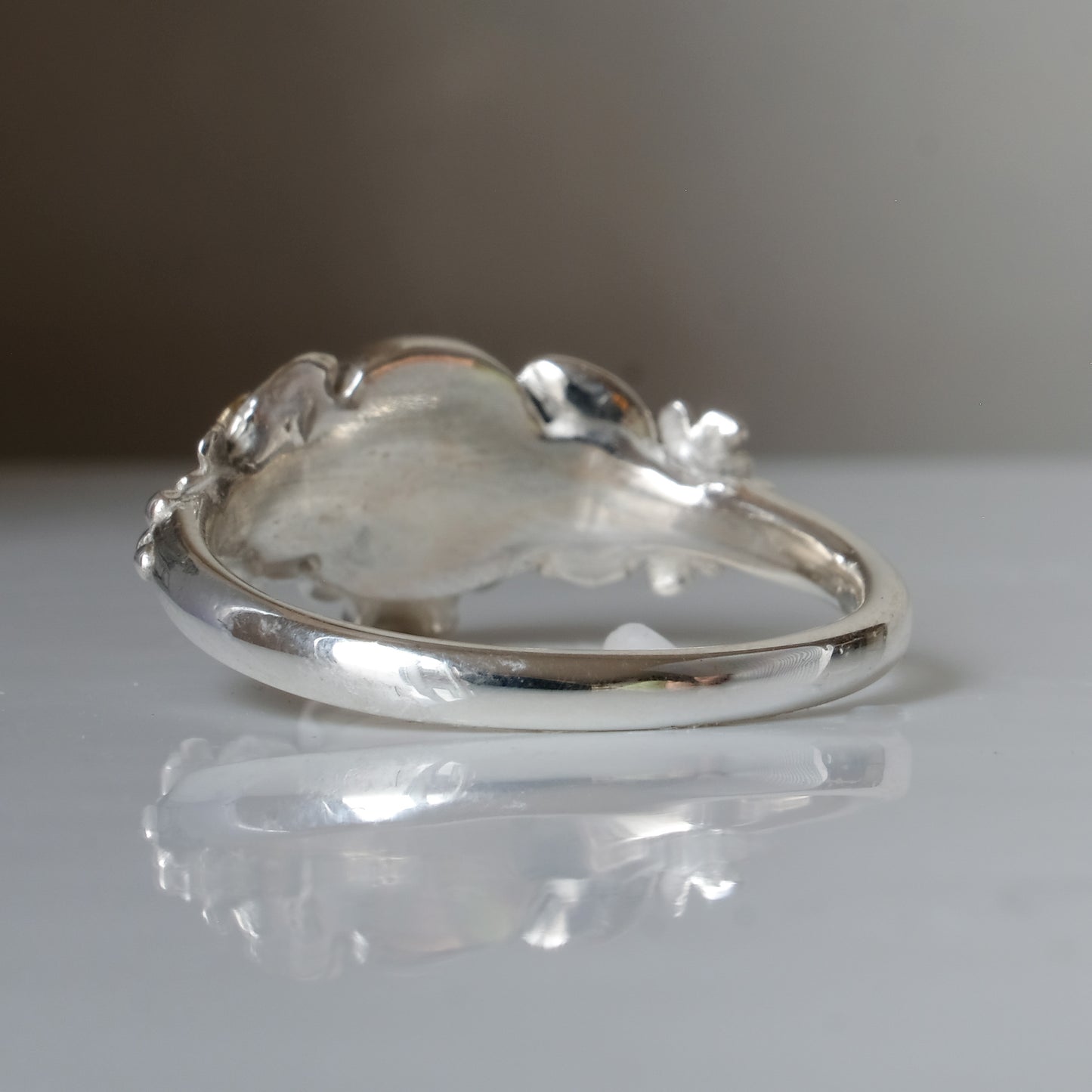 Sterling silver ring with central skull and 9ct yellow gold flower and leaves cascading down band. Handmade in London by Charlie Shires