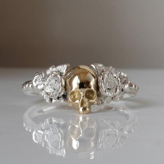 Sterling silver ring with central 9ct yellow gold skull and flower and leaves cascading down band. Handmade in London by Charlie Shires